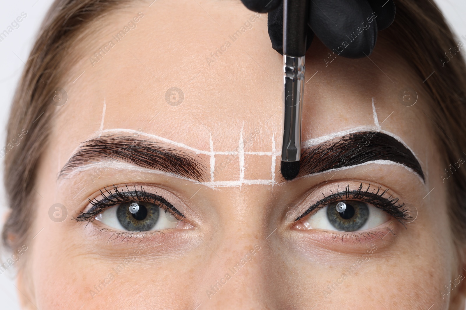 Photo of Young woman undergoing henna eyebrows dyeing procedure, closeup