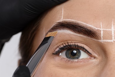 Photo of Young woman undergoing henna eyebrows dyeing procedure, closeup