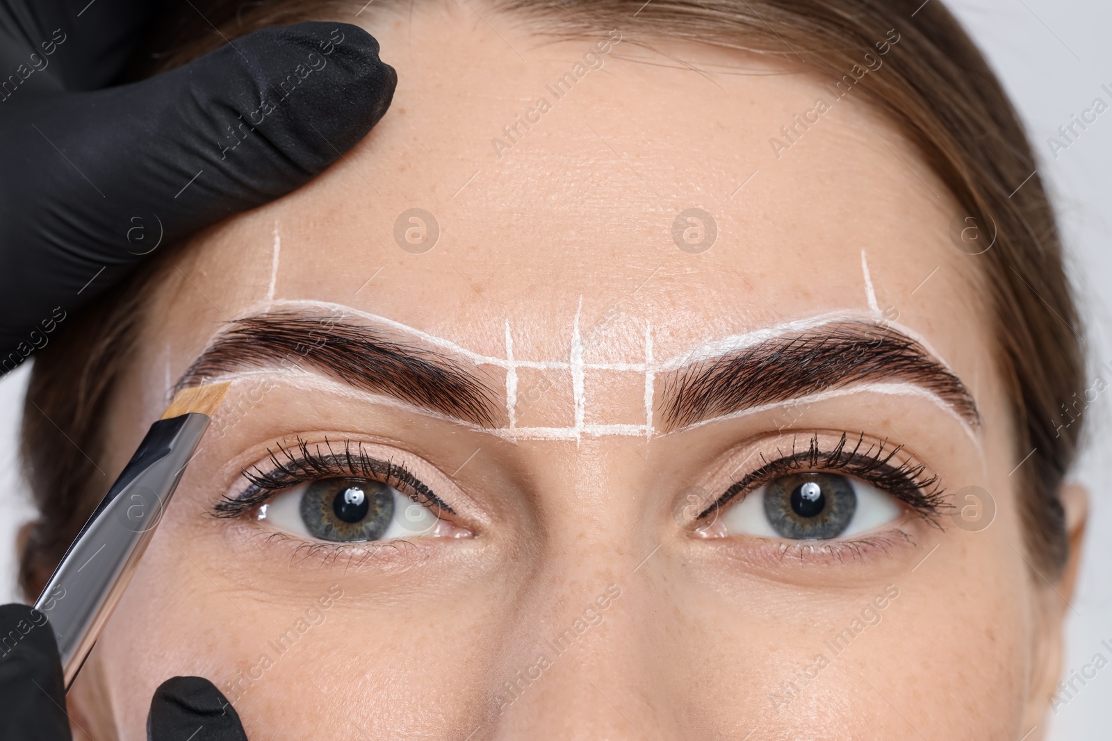 Photo of Young woman undergoing henna eyebrows dyeing procedure, closeup