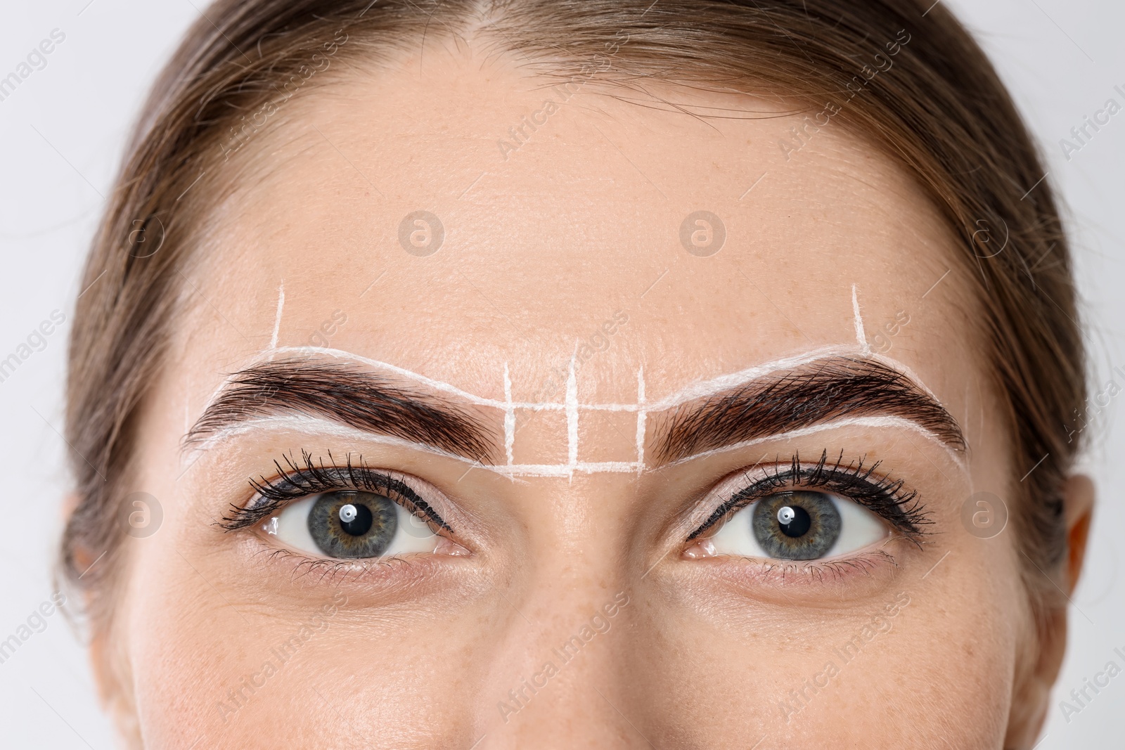 Photo of Young woman during henna eyebrows dyeing procedure on light background, closeup