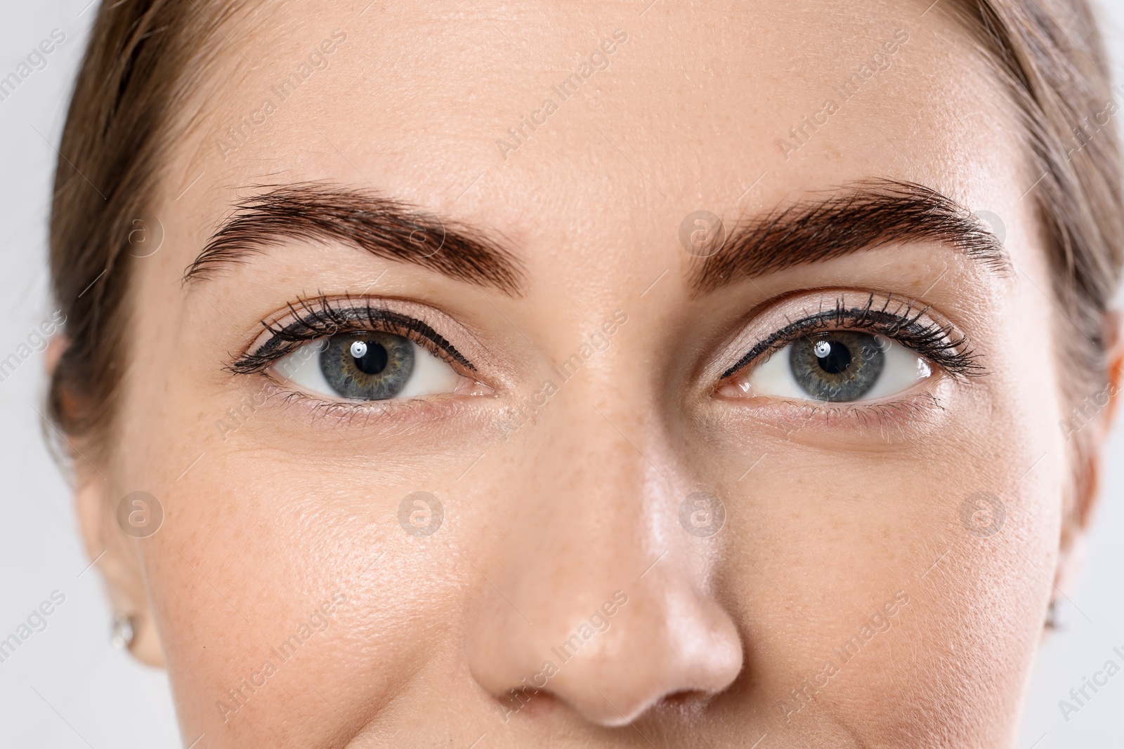 Photo of Beautiful young woman after henna eyebrows dyeing on light background, closeup