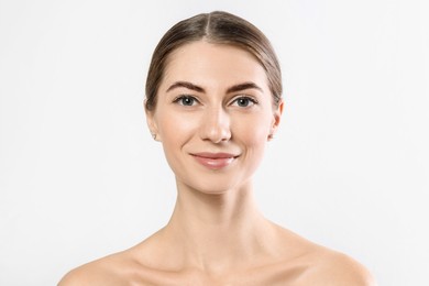 Beautiful young woman after henna eyebrows dyeing on light background, closeup