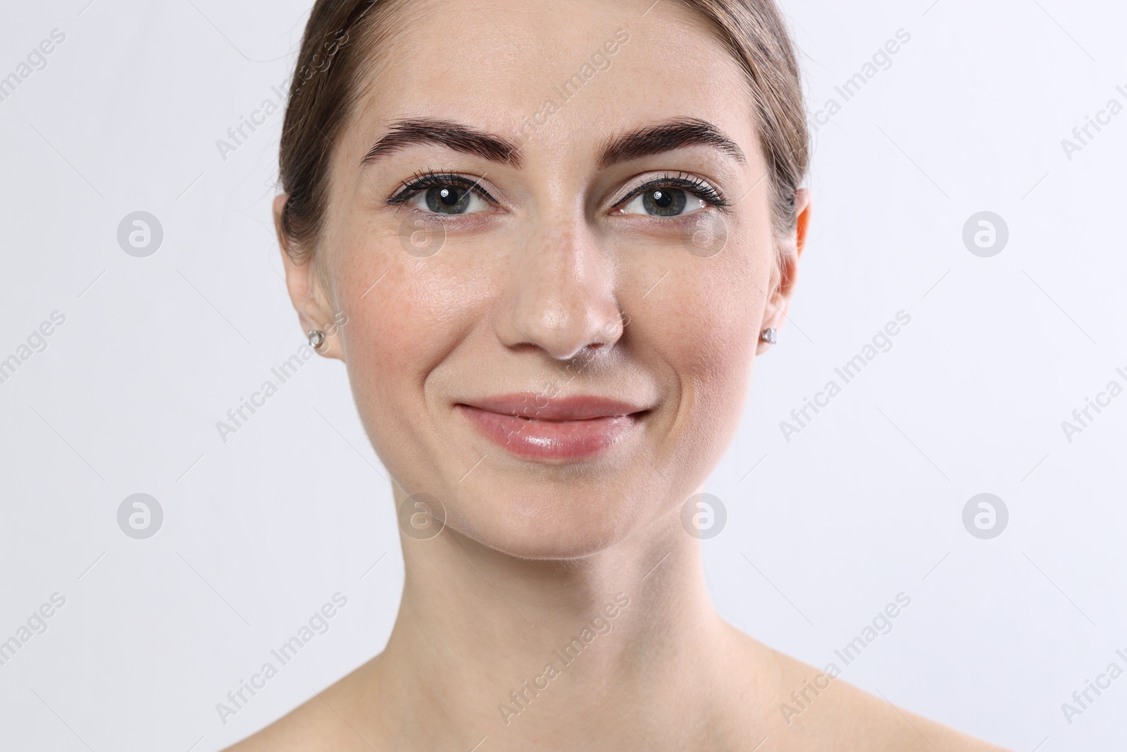 Photo of Beautiful young woman after henna eyebrows dyeing on light background, closeup