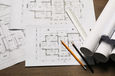 Different architectural drawings, ruler and pencils on wooden table, top view