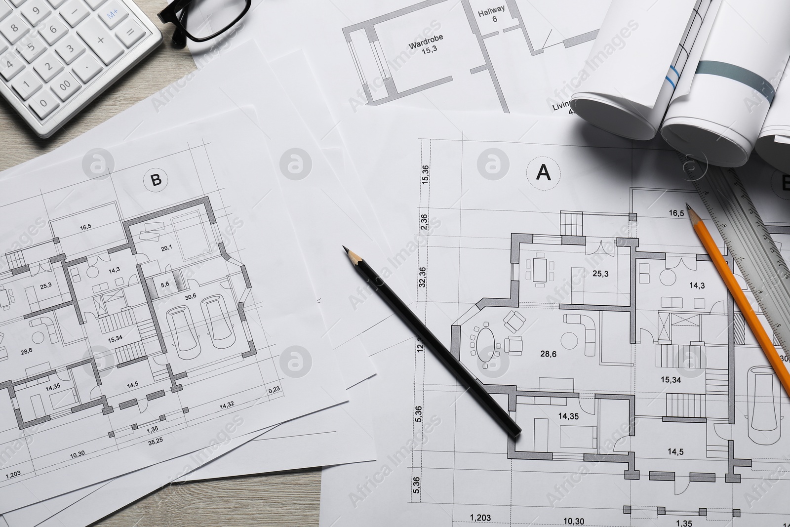 Photo of Different architectural drawings, calculator, ruler and pencils on wooden table, flat lay