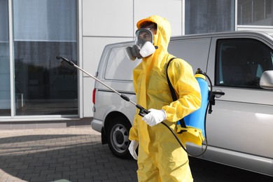 Photo of Pest control worker with spray tank outdoors