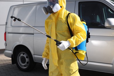 Photo of Pest control worker with spray tank outdoors