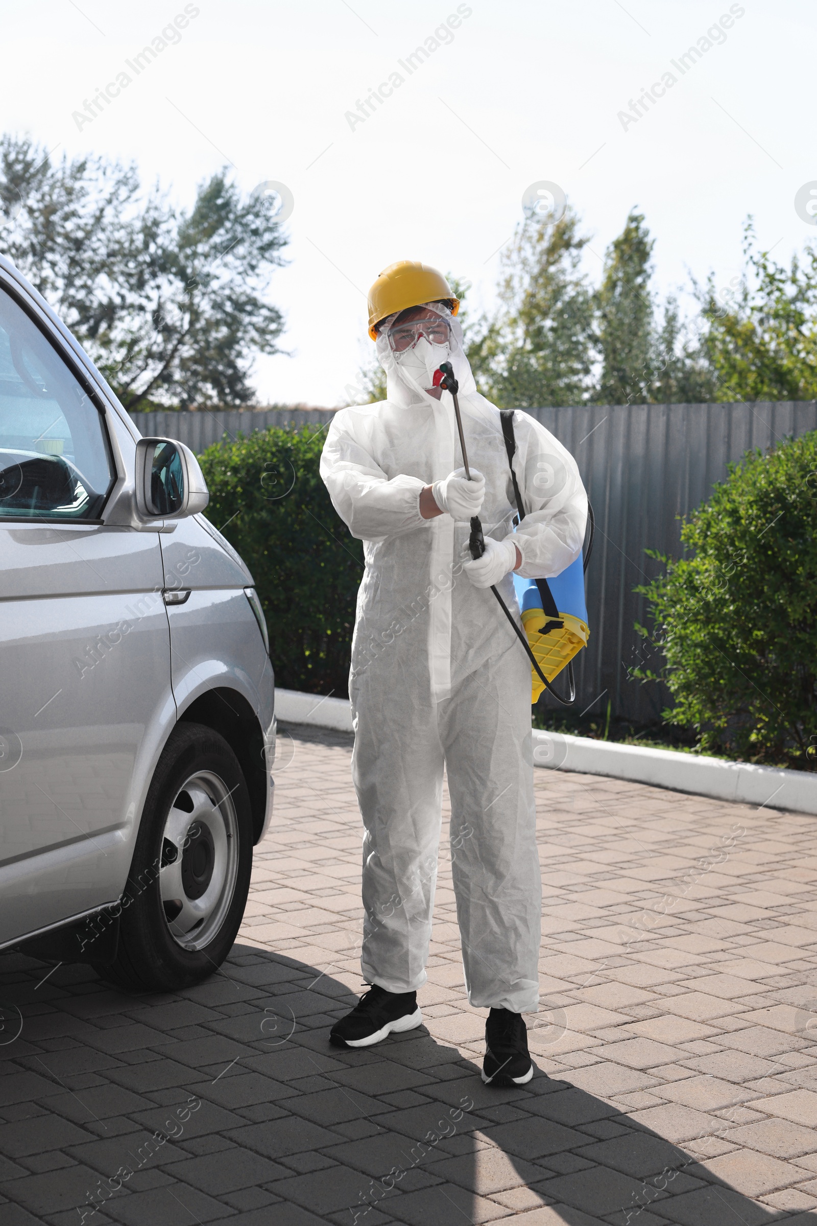 Photo of Pest control worker with spray tank outdoors