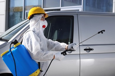 Pest control worker with spray tank near gray minibus outdoors