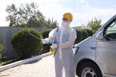 Pest control worker with spray tank outdoors