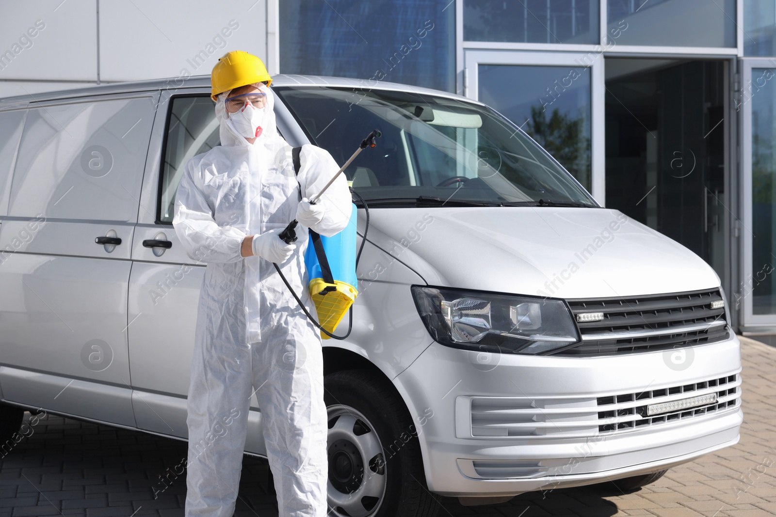 Photo of Pest control worker with spray tank near gray minibus outdoors