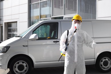 Photo of Pest control worker with spray tank showing thumbs up outdoors