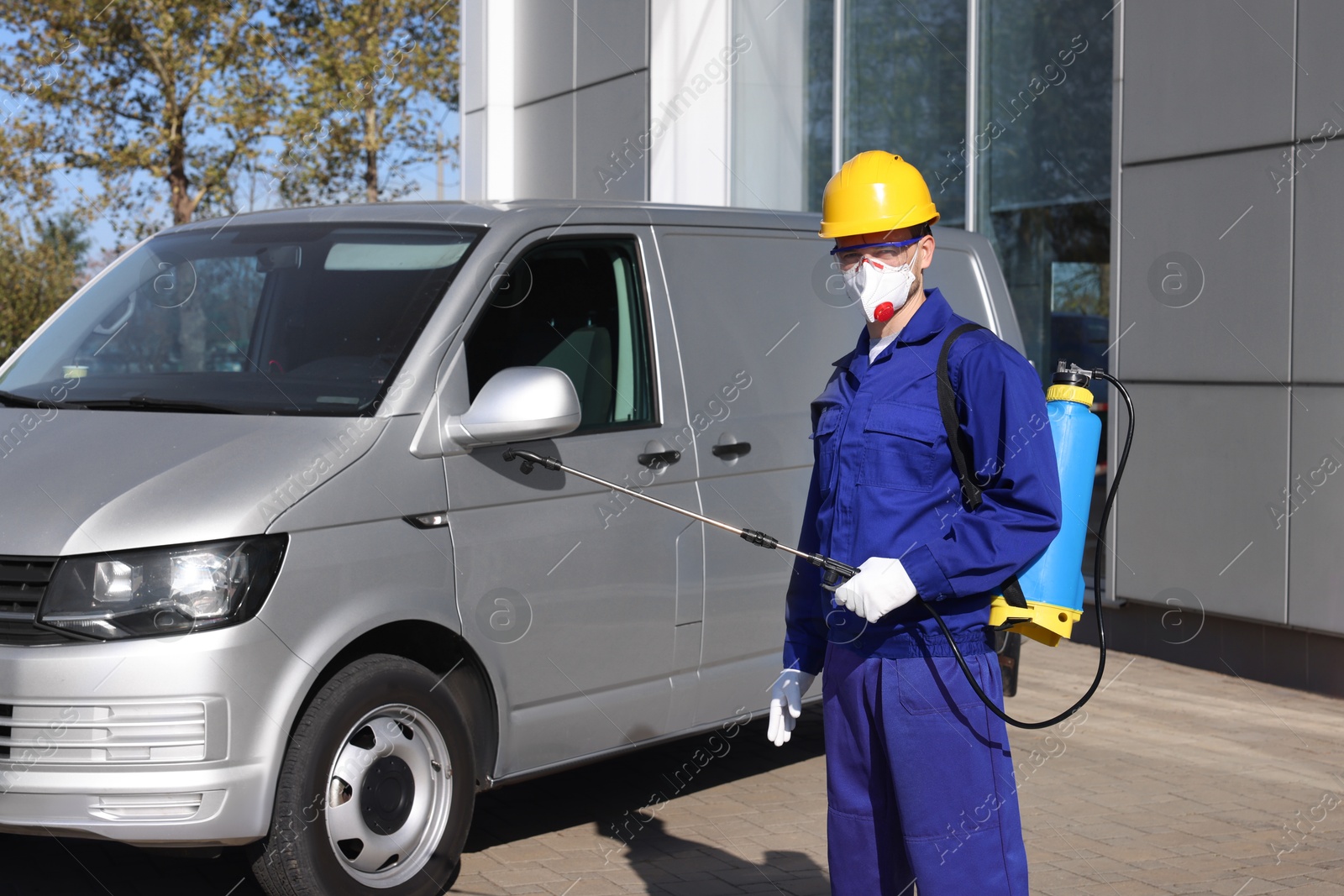 Photo of Pest control worker with spray tank outdoors