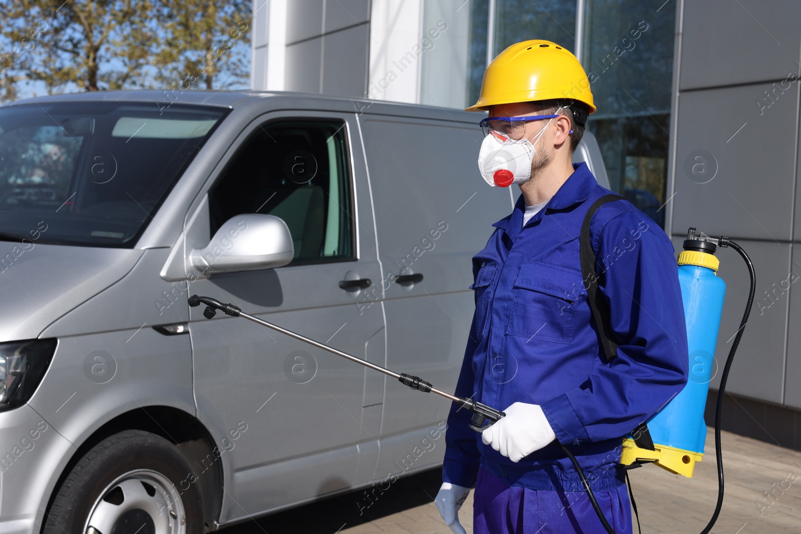 Photo of Pest control worker with spray tank near gray minibus outdoors