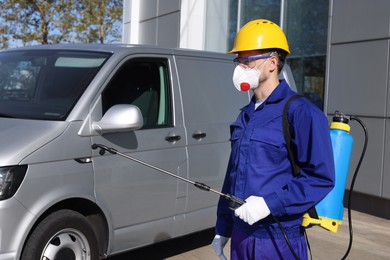 Pest control worker with spray tank near gray minibus outdoors