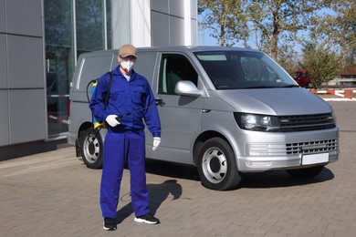 Photo of Pest control worker with spray tank outdoors