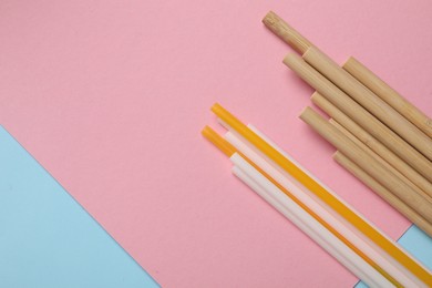 Photo of Plastic and bamboo drinking straws on color background, flat lay. Space for text