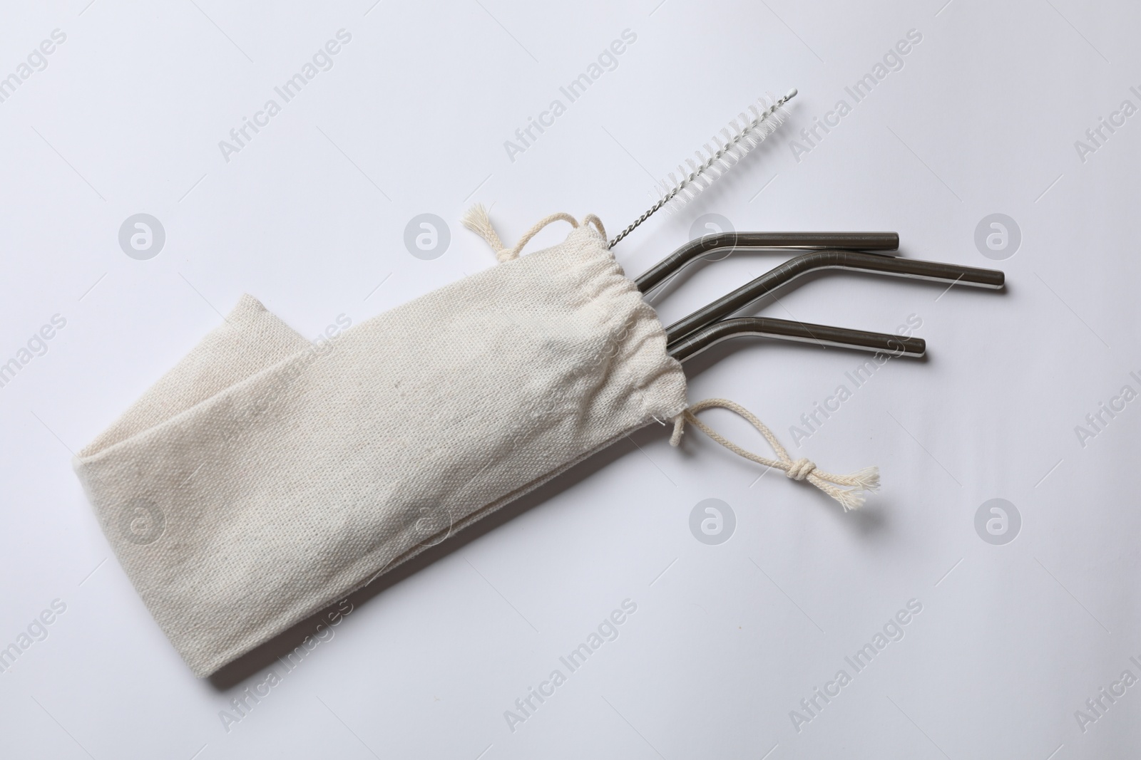 Photo of Metal drinking straws and cleaning brush in bag on white background, top view