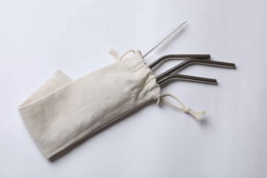 Photo of Metal drinking straws and cleaning brush in bag on white background, top view