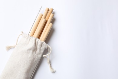 Photo of Bamboo drinking straws and cleaning brush in bag on white background, top view. Space for text