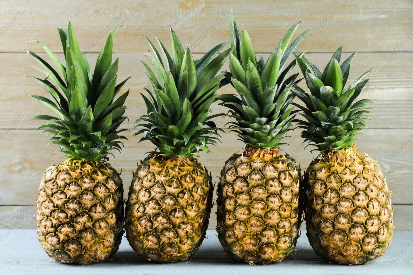 Photo of Fresh ripe pineapples on grey wooden table