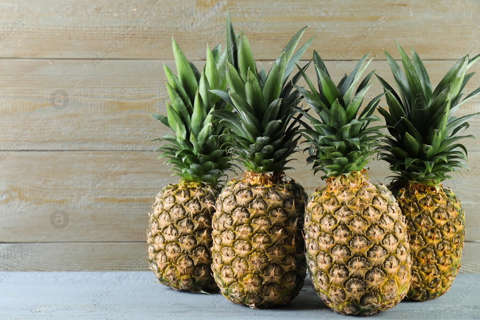 Photo of Fresh ripe pineapples on grey wooden table