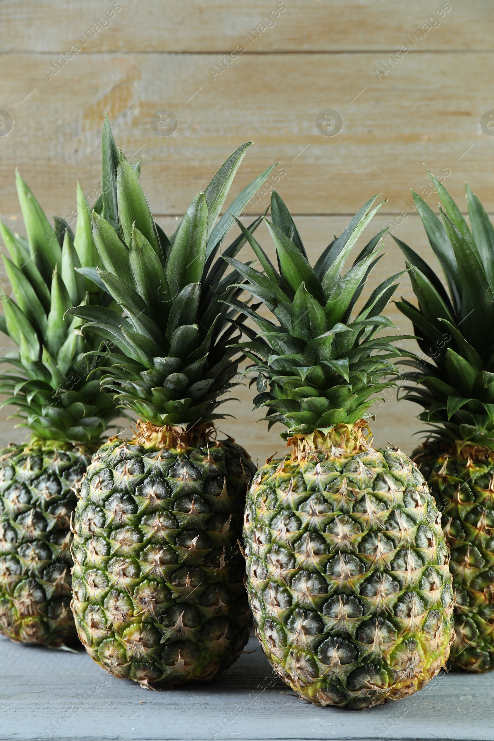 Photo of Fresh ripe pineapples on grey wooden table