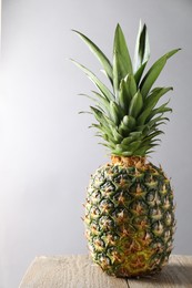 Photo of Fresh ripe pineapple on wooden table against light grey background