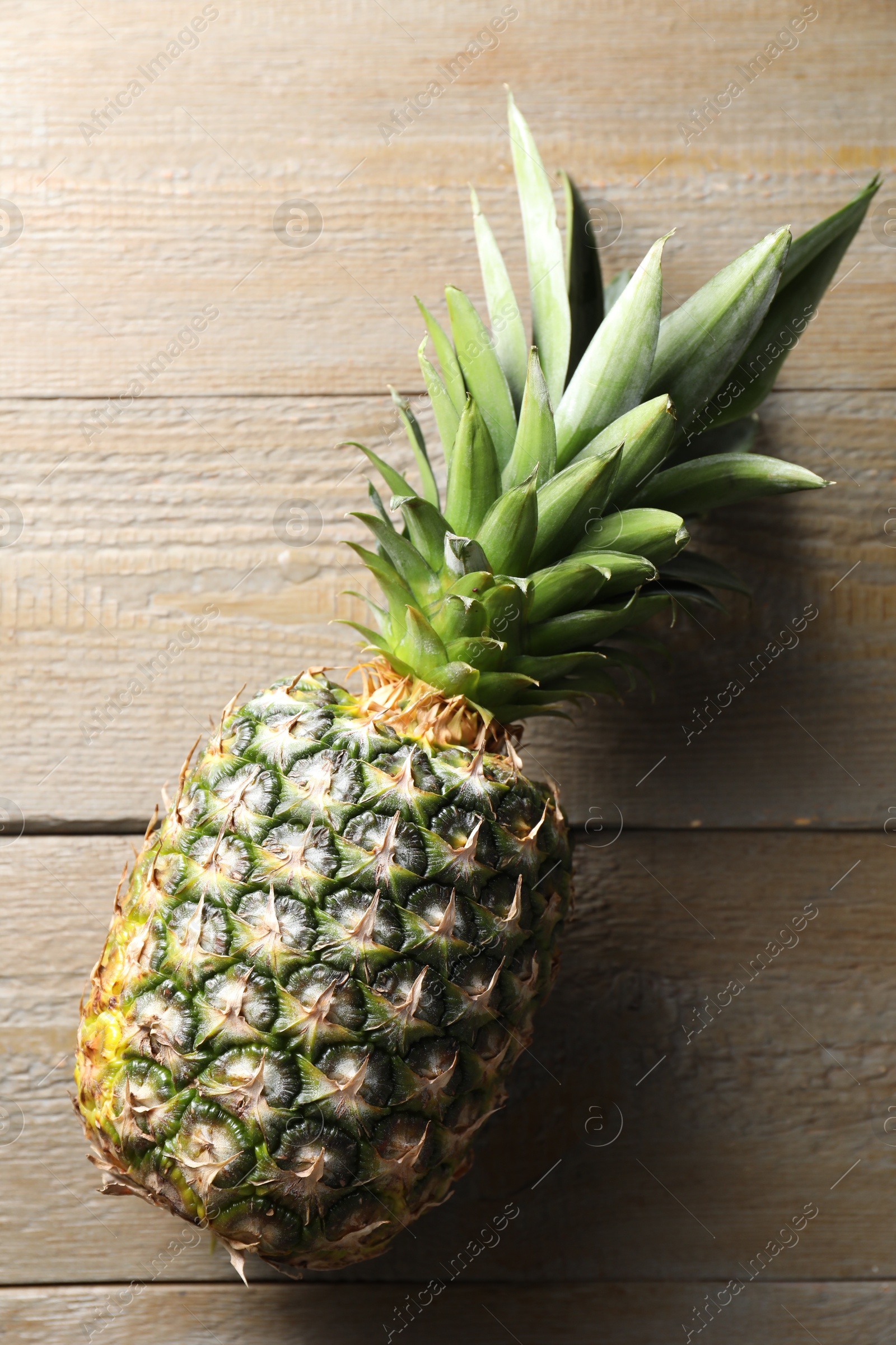 Photo of Fresh ripe pineapple on wooden table, top view