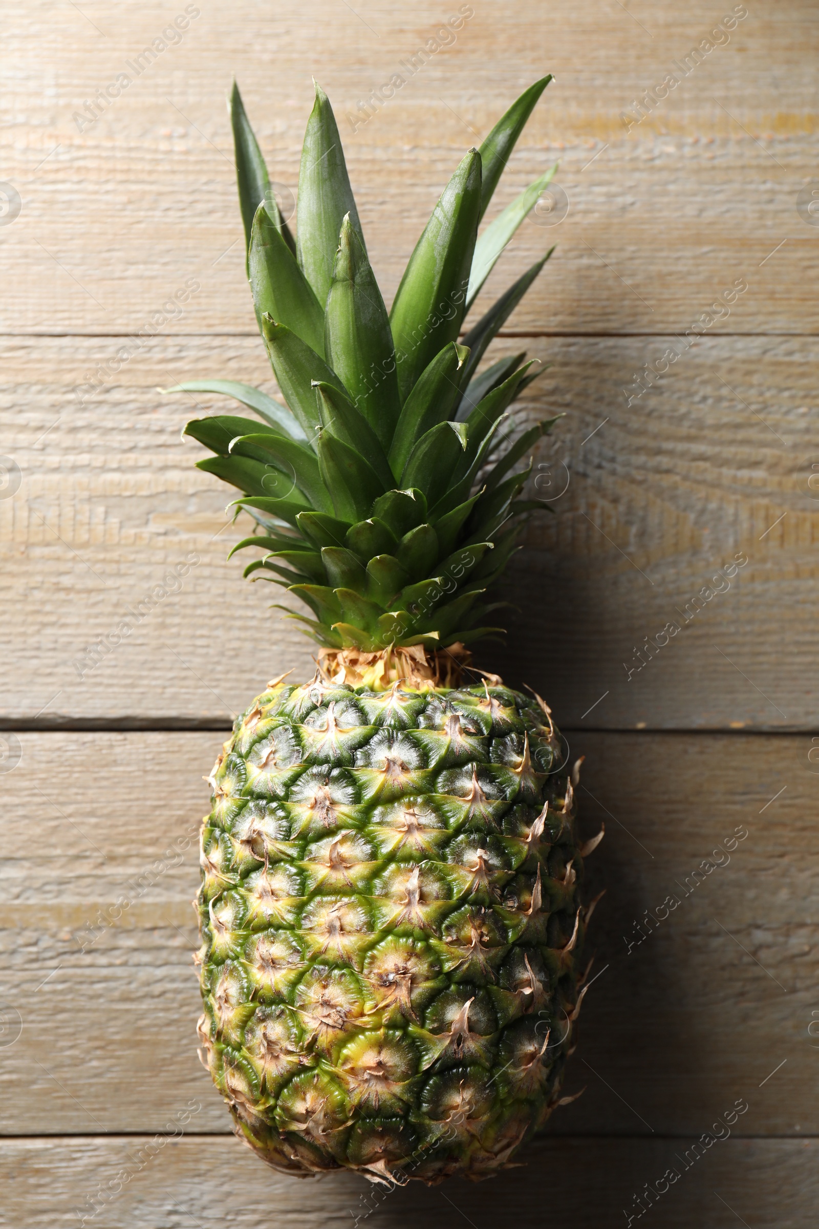 Photo of Fresh ripe pineapple on wooden table, top view