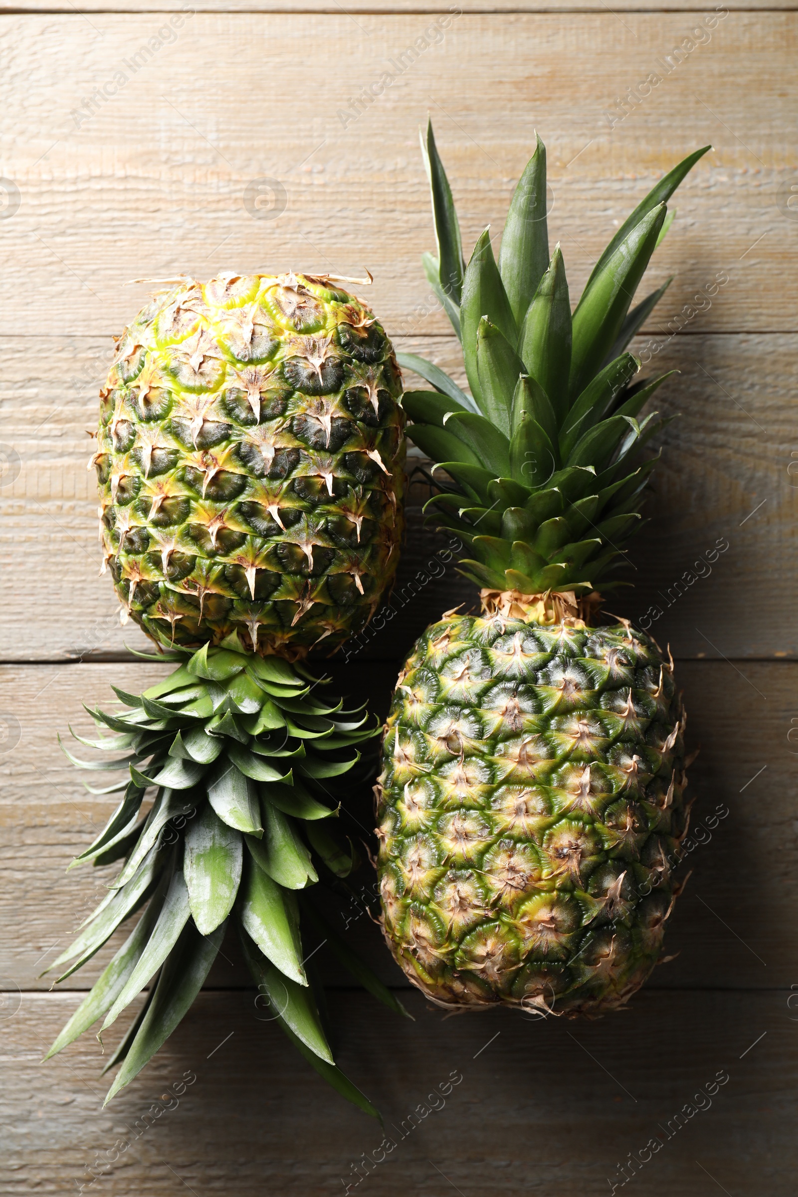 Photo of Fresh ripe pineapples on wooden table, flat lay