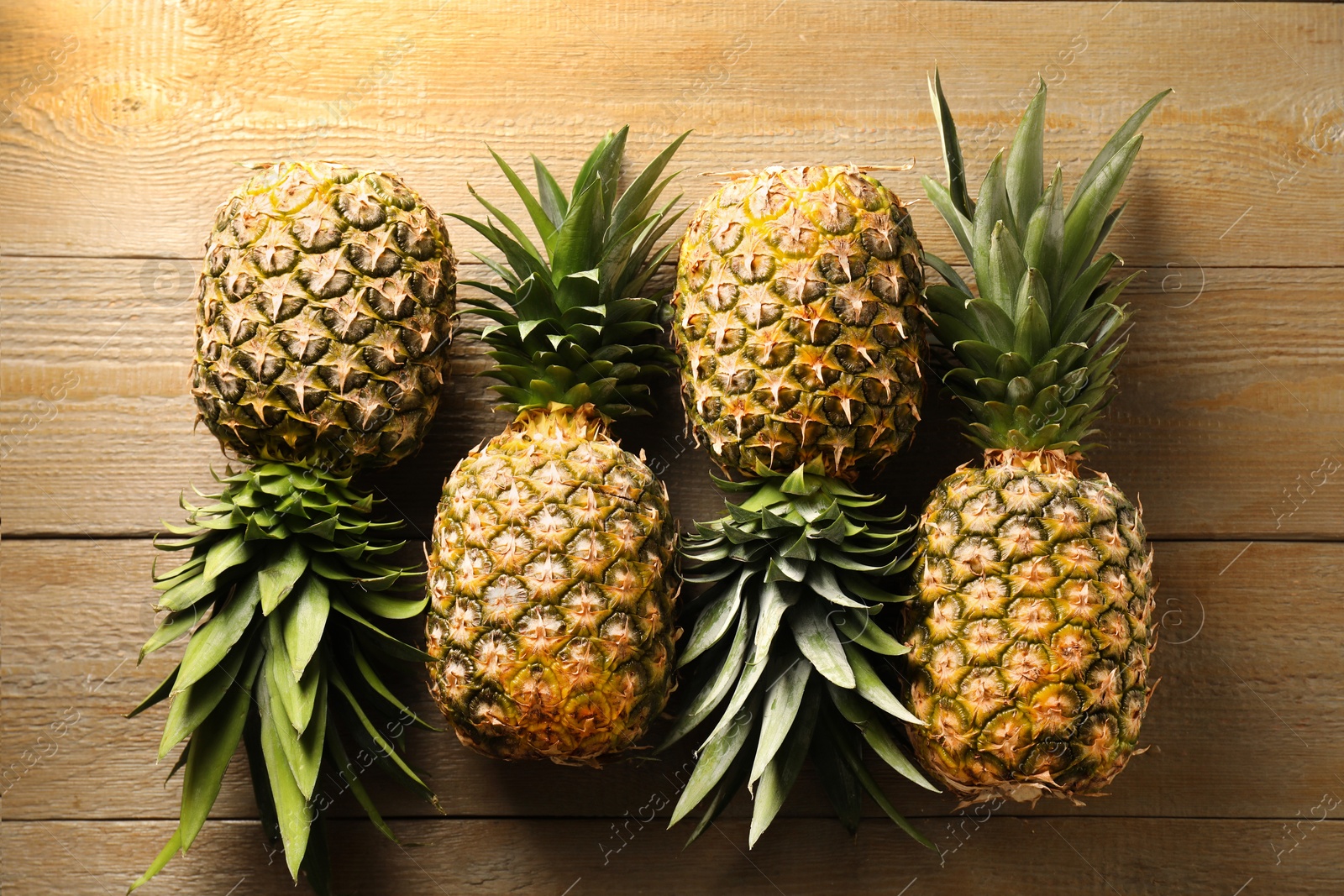 Photo of Fresh ripe pineapples on wooden table, flat lay