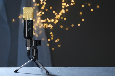 Photo of Microphone on table against dark grey background with blurred lights, space for text. Sound recording and reinforcement