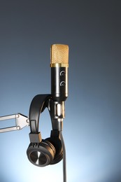 Photo of Stand with microphone and headphones on dark background. Sound recording and reinforcement