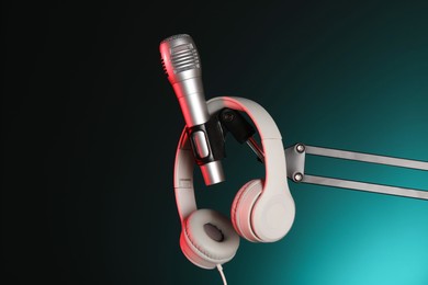 Photo of Stand with microphone and headphones on dark background. Sound recording and reinforcement