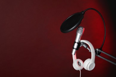 Photo of Stand with microphone, headphones and pop filter on dark background, space for text. Sound recording and reinforcement