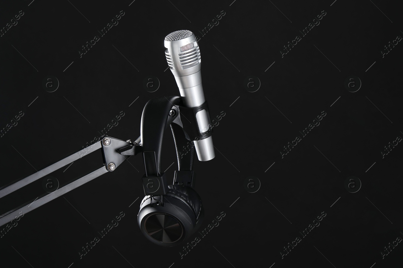 Photo of Stand with microphone and headphones on black background, space for text. Sound recording and reinforcement