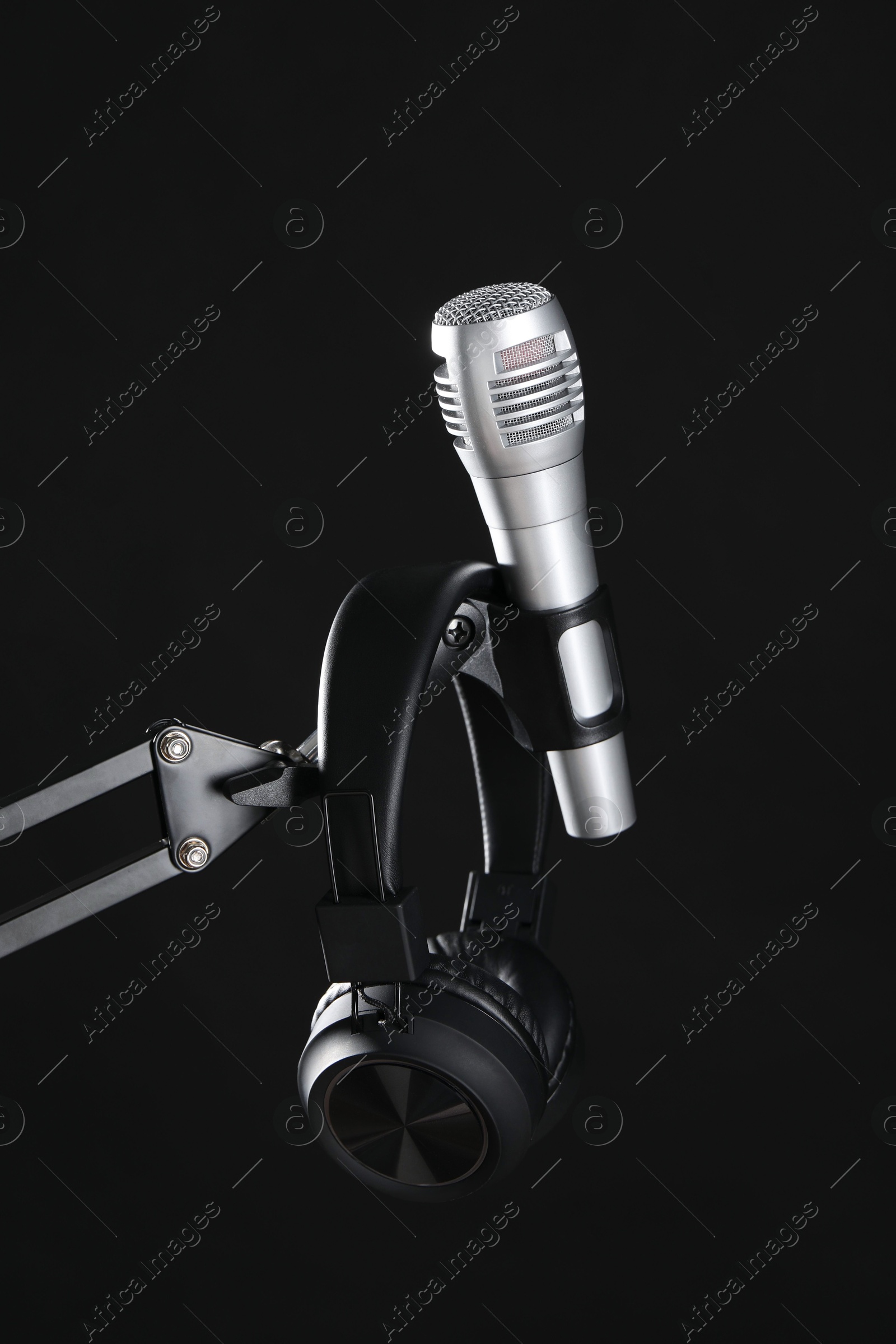 Photo of Stand with microphone and headphones on black background. Sound recording and reinforcement