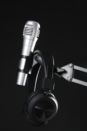 Photo of Stand with microphone and headphones on black background. Sound recording and reinforcement