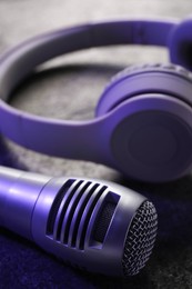 Photo of Microphone and headphones on grey textured table, closeup. Sound recording and reinforcement