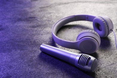 Photo of Microphone and headphones on grey textured table, closeup with space for text. Sound recording and reinforcement