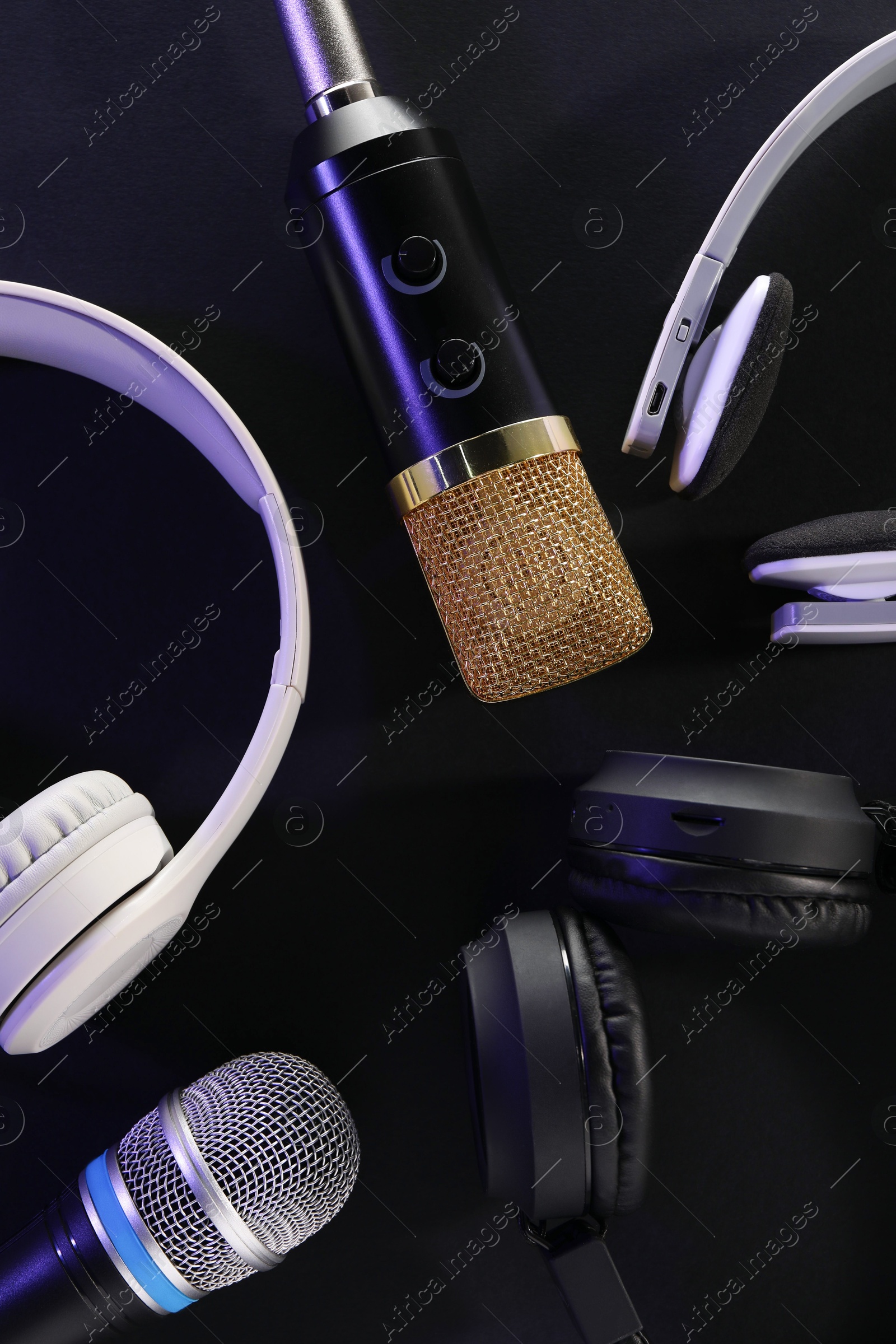 Photo of Different microphones and headphones on dark background, flat lay. Sound recording and reinforcement