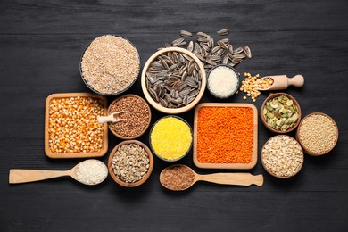 Photo of Different types of legumes, seeds and cereals on black wooden table, flat lay