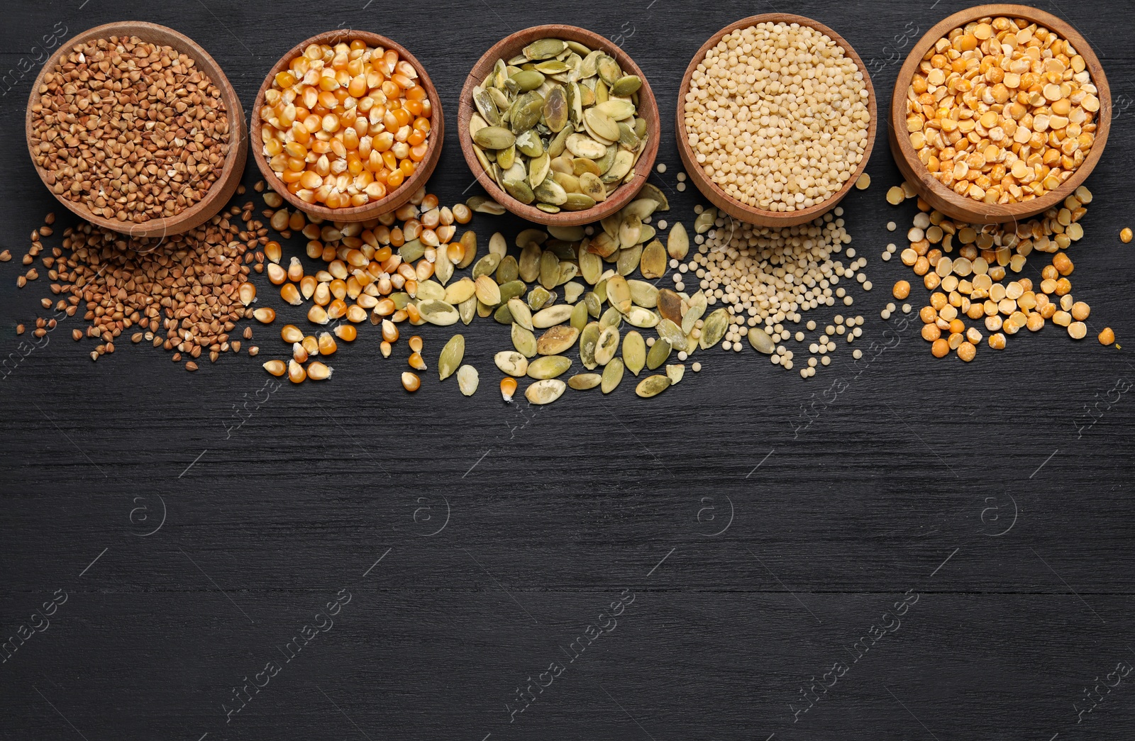 Photo of Different types of seeds and cereals in bowls on black wooden table, flat lay. Space for text