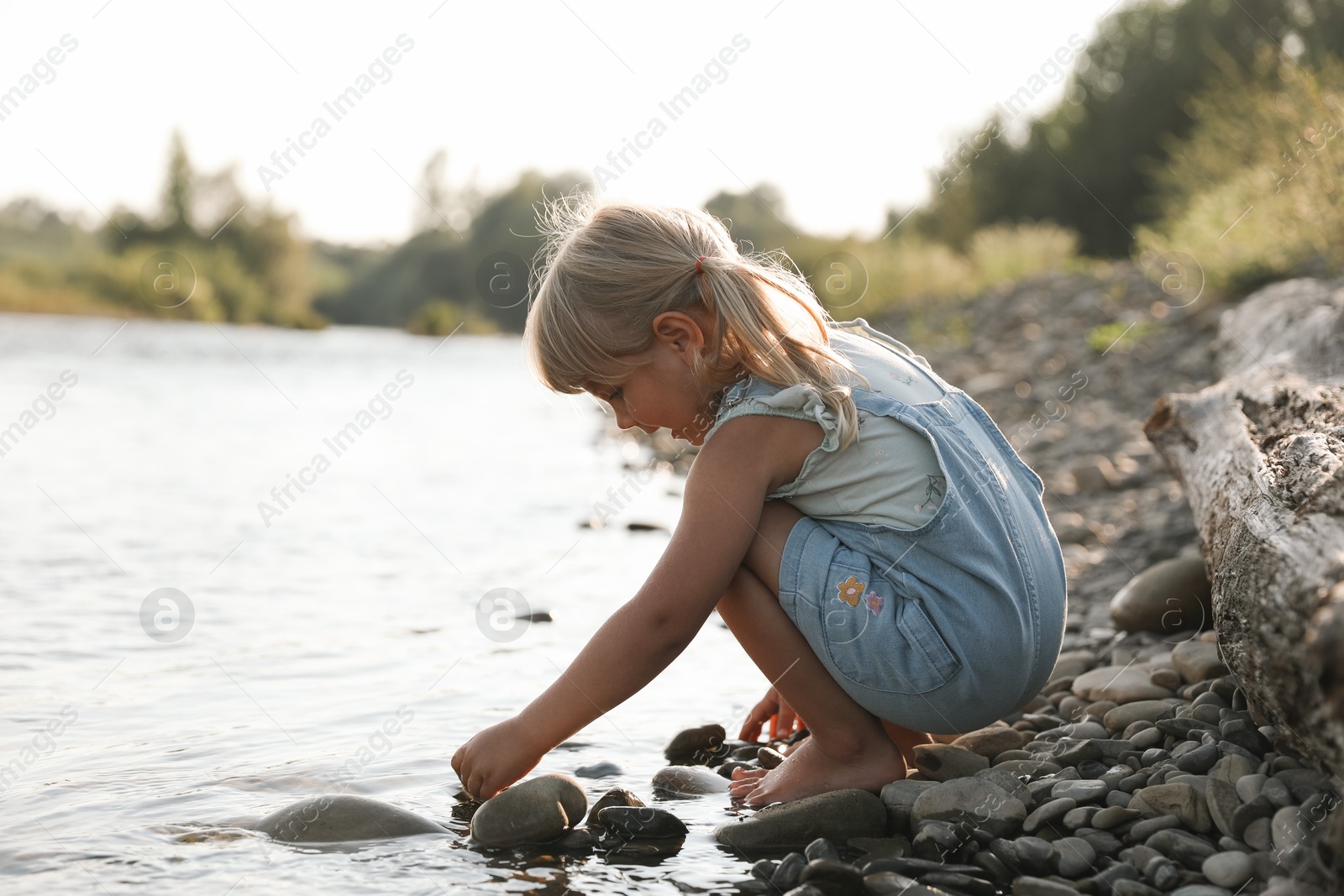 Photo of Cute little girl spending time on river. Child enjoying beautiful nature