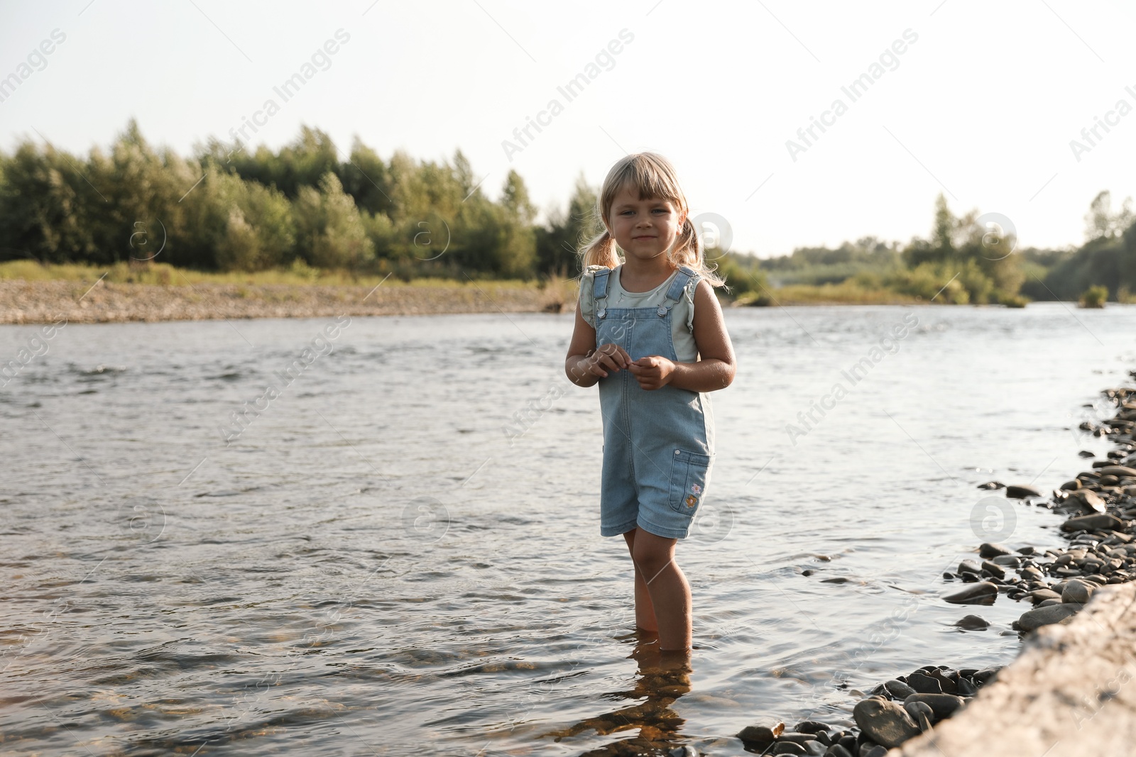 Photo of Cute little girl spending time on river. Child enjoying beautiful nature