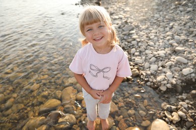 Cute little girl standing in water, above view. Child enjoying beautiful nature