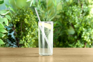 Photo of Glass of soda water with lime on wooden table against blurred background