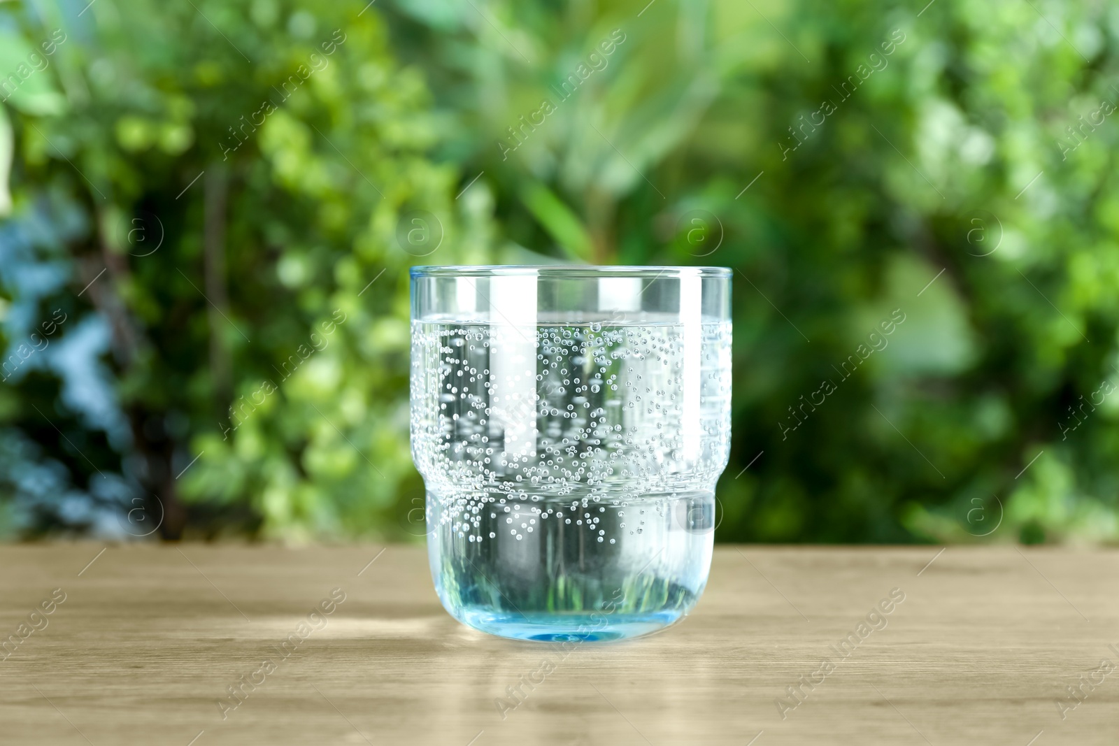 Photo of Glass of soda water on wooden table against blurred background