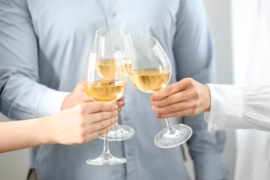 Photo of People clinking glasses of wine indoors, closeup